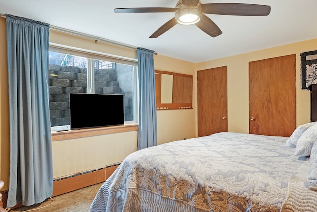 bedroom with ceiling fan, two closets, and baseboard heating