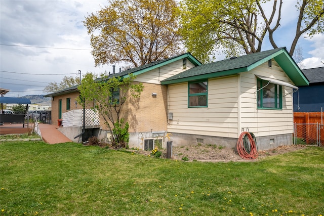 view of side of home featuring fence and a yard