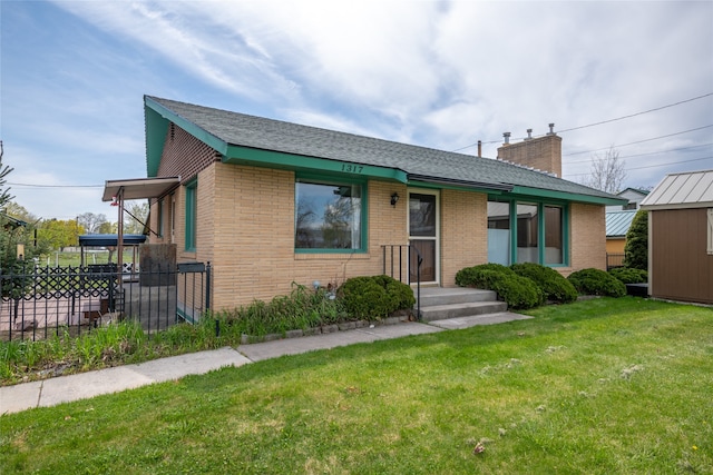 ranch-style house with brick siding, fence, a chimney, and a front yard