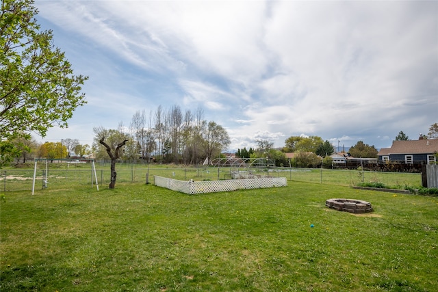 view of yard with fence, a fire pit, and a vegetable garden