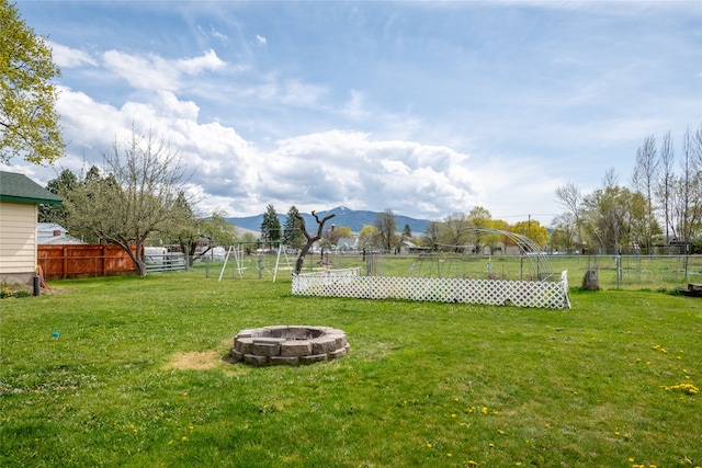 view of yard featuring a mountain view, a fire pit, and a fenced backyard