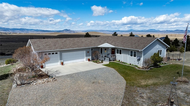 ranch-style home with a garage, covered porch, a front yard, gravel driveway, and a mountain view