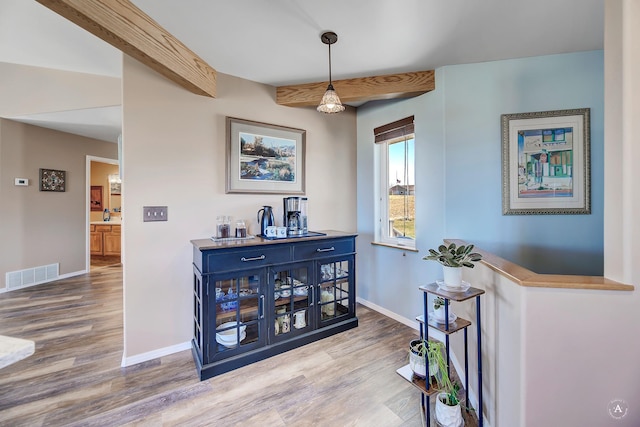 interior space featuring baseboards, beam ceiling, wood finished floors, and visible vents