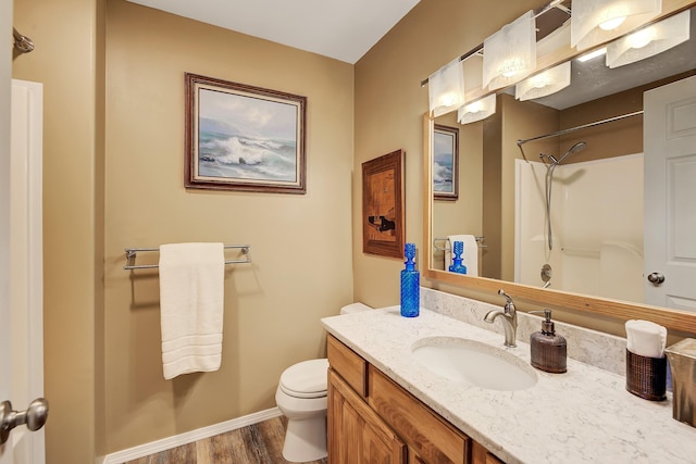 full bath featuring vanity, wood finished floors, toilet, baseboards, and walk in shower