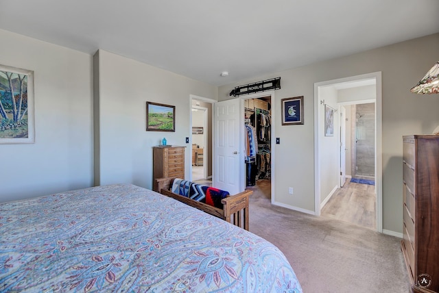 bedroom with baseboards, light colored carpet, a walk in closet, and a closet