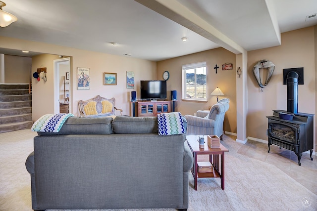 living room featuring light tile patterned flooring, a wood stove, stairs, baseboards, and visible vents