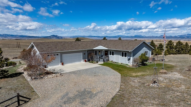 ranch-style house featuring driveway, a mountain view, a front yard, and a garage