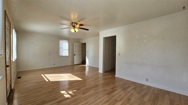 empty room featuring baseboards, ceiling fan, and light wood-style flooring