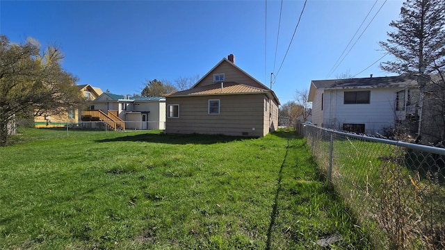 back of property featuring a lawn, metal roof, a chimney, and a fenced backyard