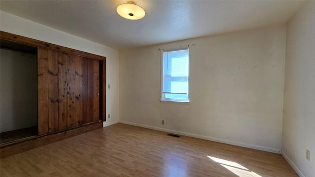 unfurnished bedroom featuring baseboards, wood finished floors, and visible vents