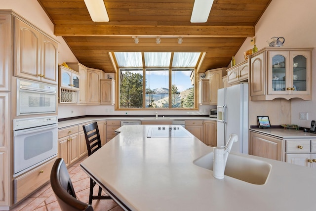 kitchen with white appliances, glass insert cabinets, vaulted ceiling with beams, wood ceiling, and a sink