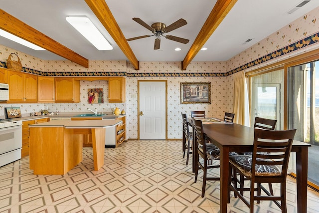 kitchen with light countertops, white appliances, beam ceiling, and visible vents