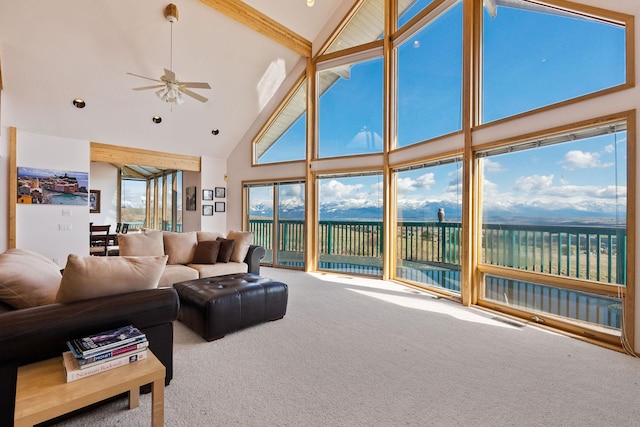carpeted living area with a water view, high vaulted ceiling, and ceiling fan