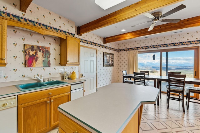 kitchen with white dishwasher, a sink, a ceiling fan, wallpapered walls, and beamed ceiling