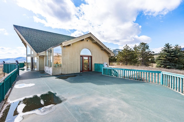 exterior space with fence and roof with shingles