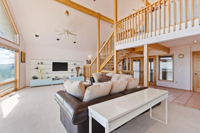 carpeted living area featuring a ceiling fan, high vaulted ceiling, and stairway