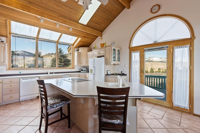 kitchen featuring a kitchen island, light tile patterned flooring, white appliances, a kitchen bar, and lofted ceiling with beams