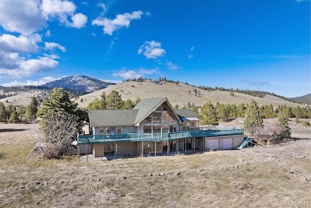rear view of house with a deck with mountain view and a garage