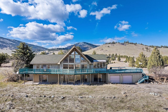 rear view of property featuring a garage and a deck with mountain view