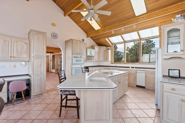 kitchen featuring a breakfast bar area, light tile patterned flooring, an island with sink, and wood ceiling