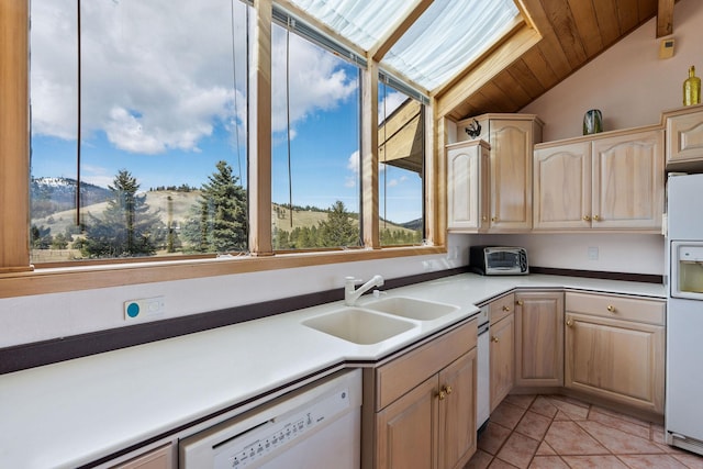 kitchen with vaulted ceiling, a sink, light brown cabinets, white appliances, and light tile patterned flooring