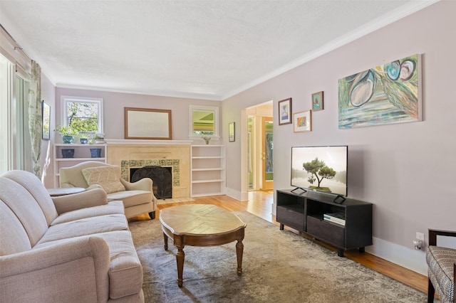 living room with crown molding, baseboards, wood finished floors, and a tile fireplace