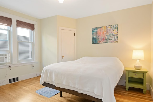 bedroom featuring baseboards, visible vents, wood finished floors, and cooling unit