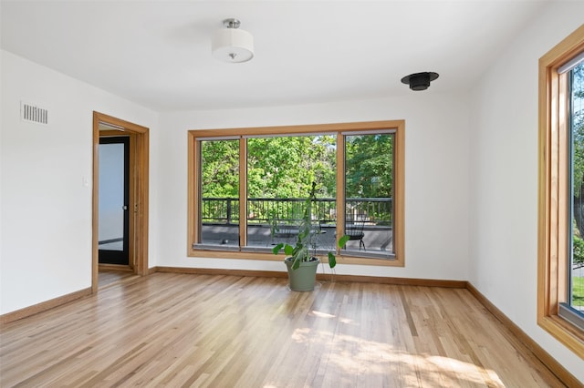 empty room with baseboards, visible vents, and wood finished floors