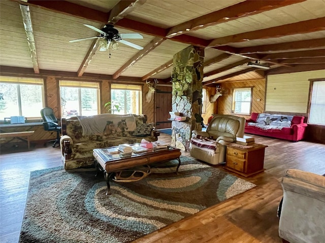 living room with wood walls, lofted ceiling with beams, plenty of natural light, and wood finished floors