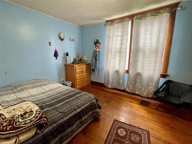 bedroom with ornamental molding, wood-type flooring, and visible vents