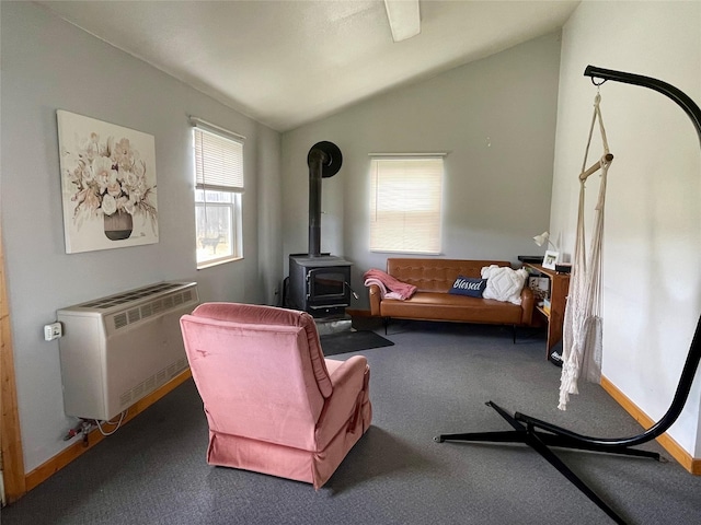 living area featuring carpet flooring, vaulted ceiling, heating unit, and a wood stove
