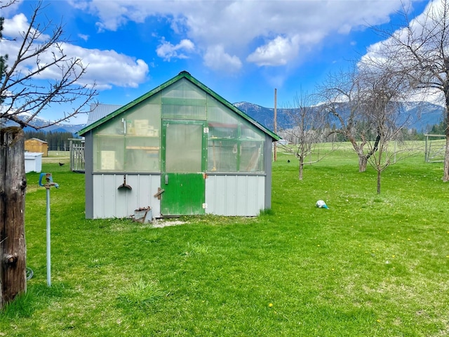 view of greenhouse featuring a lawn and a mountain view