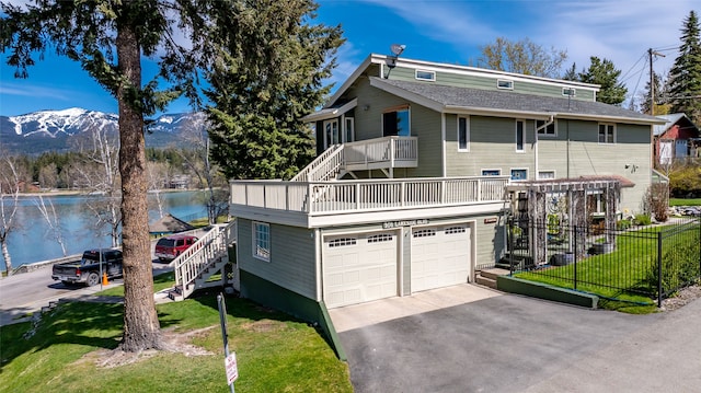 view of front of property with a garage, a front lawn, a water and mountain view, driveway, and stairway