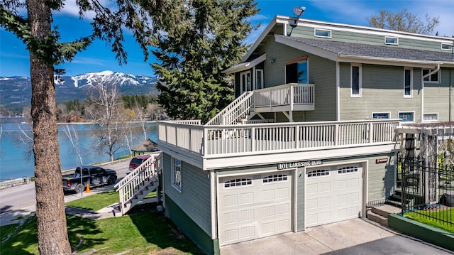 view of side of property featuring an attached garage, concrete driveway, a water and mountain view, and stairway