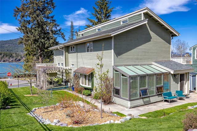 back of property with a lawn, fence, a patio, and roof with shingles