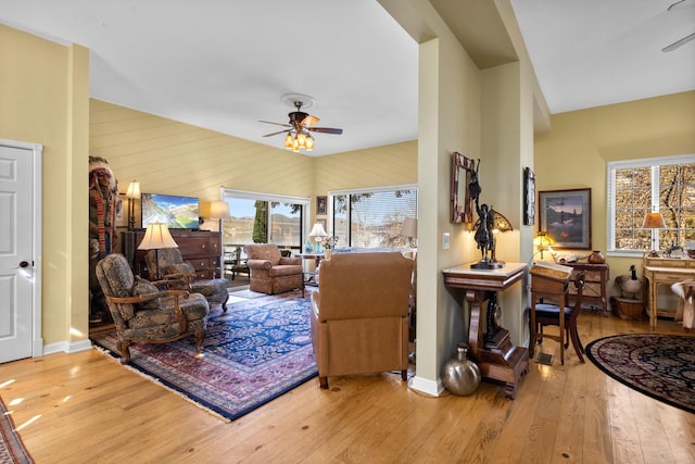 living area featuring a ceiling fan, baseboards, and hardwood / wood-style floors