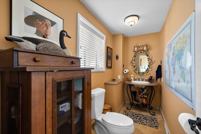 half bath featuring baseboards, a sink, and toilet