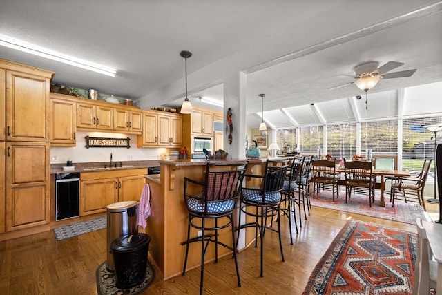 kitchen featuring light wood-type flooring, a sink, a ceiling fan, and a kitchen bar