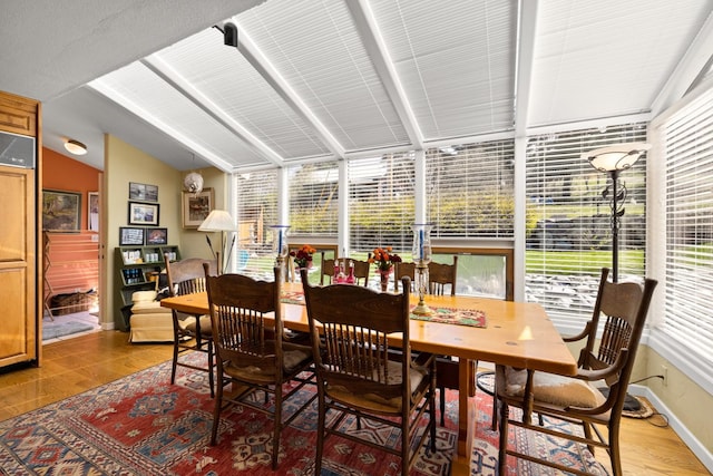 interior space featuring light wood-style floors, baseboards, lofted ceiling with beams, and a sunroom