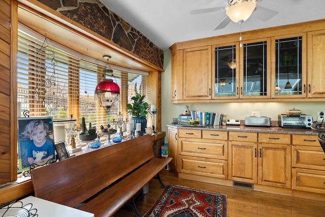 kitchen with ceiling fan, visible vents, light wood-type flooring, a toaster, and glass insert cabinets