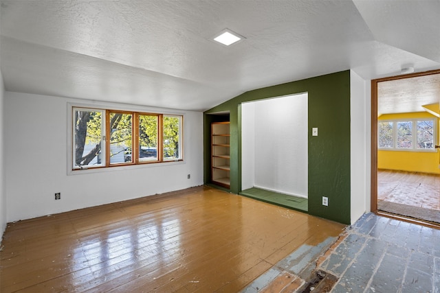 226 S Davis St, Missoula, MT 59801 - unfurnished living room featuring wood-type flooring, a textured ceiling, built in features, and lofted ceiling
