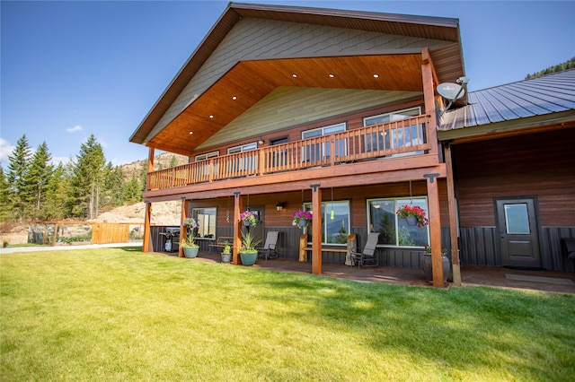 back of property featuring a lawn, a patio area, a balcony, and metal roof