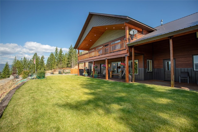 back of property with a lawn, a balcony, and a patio area