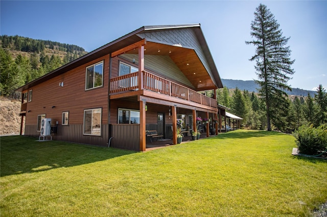back of house with a mountain view, a yard, and a forest view