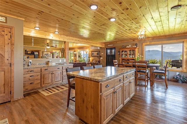 kitchen featuring dark wood-style flooring, a kitchen island, a breakfast bar, and wooden ceiling