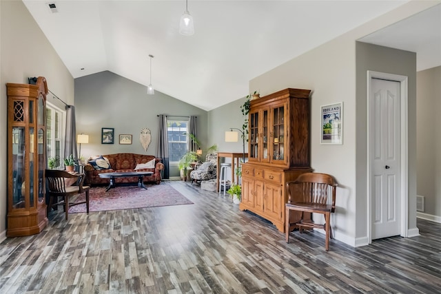 living area featuring baseboards, vaulted ceiling, wood finished floors, and visible vents