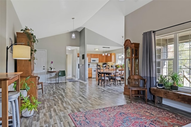 interior space with baseboards, high vaulted ceiling, and light wood-style flooring