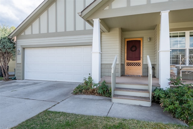 entrance to property featuring an attached garage, board and batten siding, covered porch, and concrete driveway