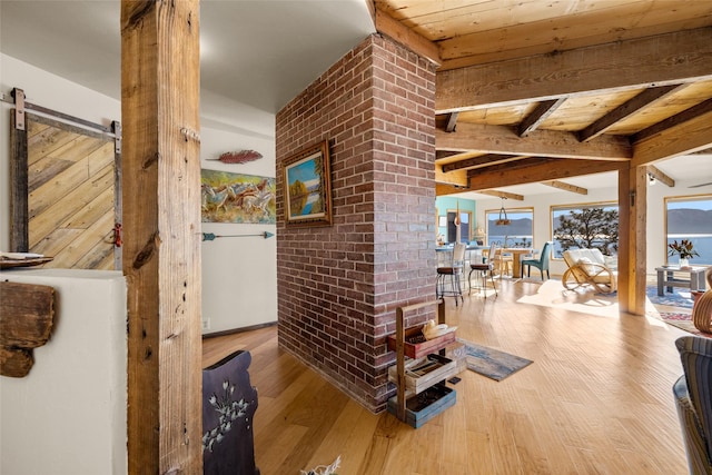 hall featuring wood-type flooring, a barn door, and beam ceiling