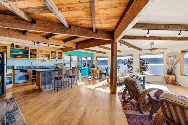 dining room featuring wood ceiling, beamed ceiling, light wood-style flooring, and wet bar